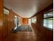 Sunroom with tile flooring and wood paneling leading into a light-filled area with a rug and glass doors at 5018 Riverside Dr, Port Orange, FL 32127