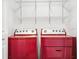 Functional laundry area featuring red front-load washer and dryer, plus overhead shelving for storage at 567 Mount Olympus Blvd, New Smyrna Beach, FL 32168