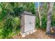 Well-maintained outdoor shed with double doors nestled among lush greenery and mature trees at 6088 Sabal Hammock Cir, Port Orange, FL 32128
