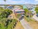 Aerial view of a charming blue two-story home with covered parking amid lush landscaping in a coastal community at 6860 Turtlemound Rd, New Smyrna Beach, FL 32169