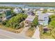 Overhead shot of a charming blue and red home surrounded by lush greenery, close to the waterway and nearby houses at 6860 Turtlemound Rd, New Smyrna Beach, FL 32169