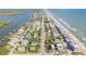 Panoramic aerial shot highlighting the house nestled between the ocean and river, surrounded by a vibrant community at 6860 Turtlemound Rd, New Smyrna Beach, FL 32169