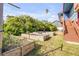 Landscaped backyard featuring raised garden beds, lush greenery, and stairs leading to the elevated blue home entrance at 6860 Turtlemound Rd, New Smyrna Beach, FL 32169