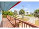 Balcony with wooden railing and views of the street, palm trees, and neighboring houses at 6860 Turtlemound Rd, New Smyrna Beach, FL 32169