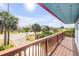Balcony with wooden railing and views of the street, palm trees, and neighboring houses at 6860 Turtlemound Rd, New Smyrna Beach, FL 32169
