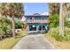 Charming blue two-story home featuring a cozy balcony, complemented by lush green foliage, and covered parking at 6860 Turtlemound Rd, New Smyrna Beach, FL 32169
