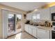 White kitchen boasts modern appliances, tiled floors, and sliding glass door to outdoor deck at 6860 Turtlemound Rd, New Smyrna Beach, FL 32169