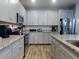 Bright kitchen with stainless appliances, granite counters, light wood floors, and gray cabinets at 727 Porter Rye Ave, Debary, FL 32713