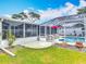 Exterior backyard view of the pool enclosure, screened in porch, patio, and lush green lawn at 805 E 15Th Ave, New Smyrna Beach, FL 32169