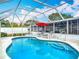 Beautiful screened pool area featuring a red umbrella, lounge chairs, and crystal clear water at 805 E 15Th Ave, New Smyrna Beach, FL 32169
