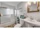 Bright bathroom featuring white subway tiles, tub with sliding glass door, pedestal sink, and rustic accents at 90 Cunningham Dr, New Smyrna Beach, FL 32168