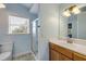 Bright bathroom with a window, shower, and vanity with wood cabinets, offering a refreshing space at 90 Cunningham Dr, New Smyrna Beach, FL 32168