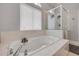 A soaking tub and glass shower are illuminated by a bright window in this sleek, white-tiled bathroom at 90 Cunningham Dr, New Smyrna Beach, FL 32168