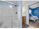 Modern bathroom featuring a tiled shower with glass door, a vanity, and a view into the adjacent blue bedroom at 90 Cunningham Dr, New Smyrna Beach, FL 32168