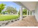 Spacious covered porch with brick flooring, elegant columns, and beautifully landscaped surroundings at 90 Cunningham Dr, New Smyrna Beach, FL 32168