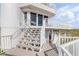 Stairway up to a coastal home with white railings and a balcony, great natural light, and ocean views at 951 N Atlantic Ave, New Smyrna Beach, FL 32169
