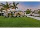 Immaculately landscaped front yard with lush green grass and mature palm trees create curb appeal at 102 Inlet Shores Dr, New Smyrna Beach, FL 32168