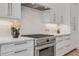 Close-up of the kitchen with stainless steel range, white cabinets, quartz countertops, and white backsplash at 102 Inlet Shores Dr, New Smyrna Beach, FL 32168