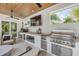 Modern outdoor kitchen with stainless steel appliances, a pizza oven, a TV, and comfortable seating under a wood ceiling at 102 Inlet Shores Dr, New Smyrna Beach, FL 32168