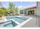 Beautiful backyard with a modern pool, spa, tanning ledge, and a covered patio with a ceiling fan at 102 Inlet Shores Dr, New Smyrna Beach, FL 32168