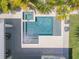 Aerial view of a modern pool with a spa and a tanning ledge surrounded by lush landscaping and a white tile patio at 102 Inlet Shores Dr, New Smyrna Beach, FL 32168