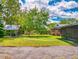 View of the backyard with a storage area, lawn and various mature trees at 108 Dee St, New Smyrna Beach, FL 32168