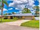 A single-story home with a concrete driveway, lush landscaping and a metal roof at 108 Dee St, New Smyrna Beach, FL 32168