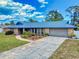 A single-story home with landscaping, palm trees, concrete driveway and a blue metal roof at 108 Dee St, New Smyrna Beach, FL 32168