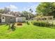 Backyard featuring a stone patio, Adirondack chairs, pergola, and mature landscaping at 1144 Corbin Park Rd, New Smyrna Beach, FL 32168