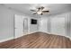 Open bedroom with ceiling fan, wood-look floors, neutral walls, tv and access to bathroom at 1144 Corbin Park Rd, New Smyrna Beach, FL 32168