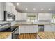 Well-lit kitchen featuring white cabinets, stainless appliances, granite countertops, and wood flooring at 1144 Corbin Park Rd, New Smyrna Beach, FL 32168