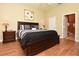A view of the main bedroom with hardwood floors, a decorative painting, and an ensuite bathroom at 1442 Carlow Cir, Ormond Beach, FL 32174