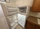 Refrigerator with its doors open, showing shelf space, along with wooden kitchen cabinets at 1600 Big Tree Rd # L1, South Daytona, FL 32119