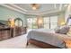 A bright main bedroom has an elegant tray ceiling, dressers, and sliding glass door access to the backyard pool at 1734 Covendale Ln, Port Orange, FL 32128