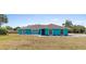 Turquoise home with a charming entrance featuring arched windows, a dark screen door, and minimal landscaping at 1845 Willow Oak Dr, Edgewater, FL 32141