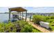 This boat dock features a covered lift, a wooden walkway, and is surrounded by lush greenery on a sunny day at 1905 S Riverside Dr, Edgewater, FL 32141