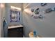 Modern powder room with vanity, bright light fixture, and decorative fish wall art at 1999 Turnbull Lakes Dr, New Smyrna Beach, FL 32168