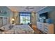 Cozy bedroom features a ceiling fan, a large window with seating, and beach-themed decor at 1999 Turnbull Lakes Dr, New Smyrna Beach, FL 32168