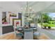 Well-lit dining room featuring a modern chandelier, glass table, and views of the backyard at 2005 Country Club Dr, Port Orange, FL 32128