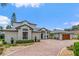 Beautiful home featuring a circular brick driveway, lush landscaping, and a wooden garage door at 2005 Country Club Dr, Port Orange, FL 32128