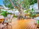 Relaxing backyard features a wooden deck with ample seating under a lush, mature tree canopy at 216 Murray St, New Smyrna Beach, FL 32168