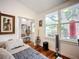 Sunlit bedroom boasts hardwood floors, views of the landscaped backyard through large windows at 216 Murray St, New Smyrna Beach, FL 32168