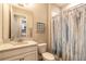 Bright bathroom featuring a vanity with granite counters, framed mirror, and shower with decorative blue curtain at 219 Venetian Palms Blvd, New Smyrna Beach, FL 32168
