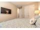 Bedroom featuring a large screen TV, a plush patterned bed, and a view into an adjoining room at 219 Venetian Palms Blvd, New Smyrna Beach, FL 32168
