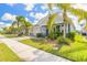 Charming home exterior with a well-maintained lawn, mature landscaping, and a welcoming entrance at 219 Venetian Palms Blvd, New Smyrna Beach, FL 32168