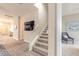 Bright hallway with wood-look tile flooring, a staircase, and a view into a bedroom at 219 Venetian Palms Blvd, New Smyrna Beach, FL 32168