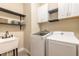 Functional laundry room with modern washer and dryer, a utility sink, and ample shelving for storage at 219 Venetian Palms Blvd, New Smyrna Beach, FL 32168