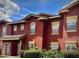 Two-story townhouse with red stucco exterior and manicured landscaping at 240 Villa Di Este Ter # 212, Lake Mary, FL 32746