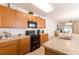 Well-lit kitchen with wood cabinets, black appliances, and a view of the dining area at 2818 Taton Trce, New Smyrna Beach, FL 32168