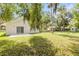 Overgrown backyard with green grass and mature trees behind the home at 2822 Brookline Ave, New Smyrna Beach, FL 32168